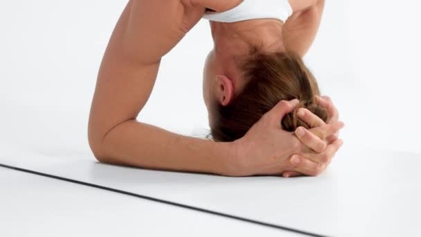 Mujer mayor en el espacio blanco practica yoga Primer plano inclinación movimiento mostrando un soporte de cabeza — Vídeos de Stock