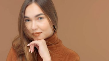 Monochrome brown look of caucasian woman in studiowith hand support her face