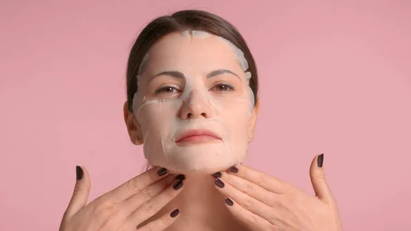 30s brunette woman closeup portrait showing a sheet mask on. Self-care concept — Stock Photo, Image