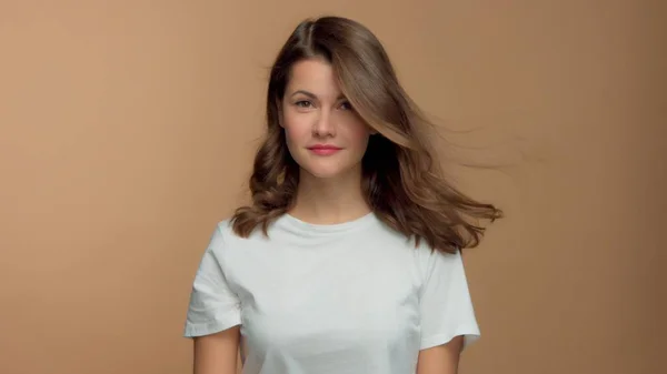 Monochrom natürliches Make-up Look kaukasische Frau in weißem T-Shirt im Studio mit brünetten glänzenden welligen Haaren weht — Stockfoto