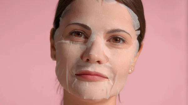 30s brunette woman closeup portrait showing a sheet mask on. Self-care concept — Stock Photo, Image