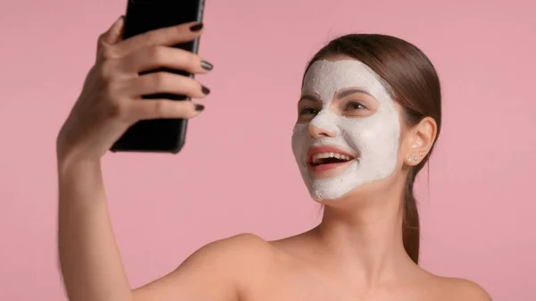 Wanita berambut cokelat 30-an dengan masker tanah liat untuk membuat selfie dengan smartphone — Stok Foto