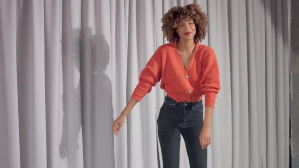 Mixed race woman on grey curtains background is dancing — Stock video