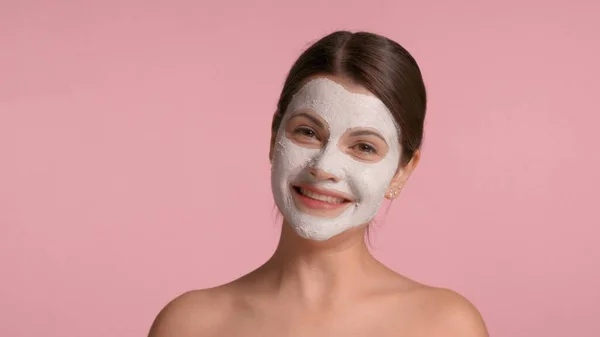 30-летняя брюнетка в маске из глины на лице смеется и веселится, делая лица — стоковое фото