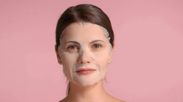 30s brunette woman closeup portrait showing a sheet mask on. Self-care concept — Stock Photo, Image