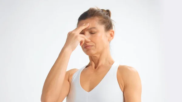 Senior woman in white space practice yoga during breathing exercises closes her nose — Stok fotoğraf