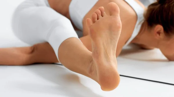 Senior woman in white space practice yoga closeup of toe in a turtle pose — Stock Fotó