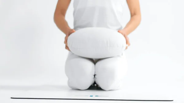 Неузнаваемая женщина в белом пространстве с подушкой для йоги — стоковое фото