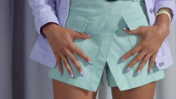 Onherkenbare vrouw in pastel kleur kleding met lila metalen manicure zet haar handen op zakken — Stockvideo