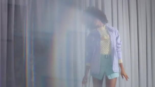 Танцівниця змішаної раси на сірих шторах в пастельних кольорах одяг танцює і відео через кристал зі світлими відображеннями — стокове відео