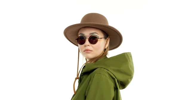 Frau im Herbstlook im Atelier in grünem Parka und Hut dreht sich um und posiert vor der Kamera — Stockfoto
