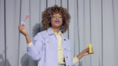 Gri perdelerde karışık yarış dansçısı. Arka planda pastel renkte. Kıyafetler dans ediyor ve köpükler yapıyor.