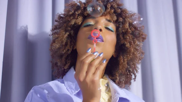 Gemengd ras zwarte vrouw met krullend haar en gloed make-up blow maken babbels — Stockfoto