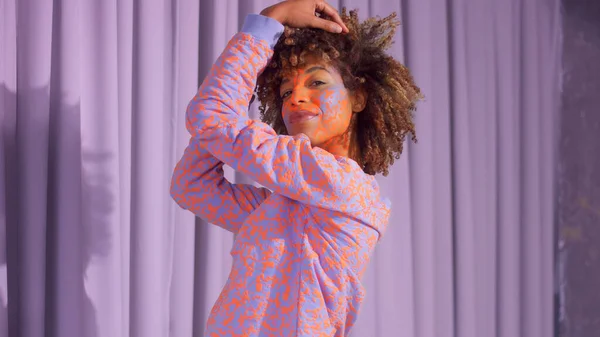 Mixed race woman with curly hair and bright neon makeup pattern on the face the same like on her sweatshirt — Stock Photo, Image