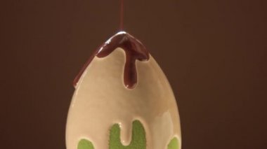 Bir yumurta şekilli blender süngeri. Hafif sıvı temel rengiyle kaplanmış ve koyu renk üzerine dökülüyor.