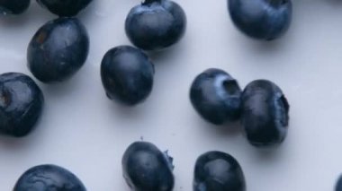 Yaban mersinleri süper yavaş çekimde yukarıdan beyaz masa görüntüsüne düşüyorlar.