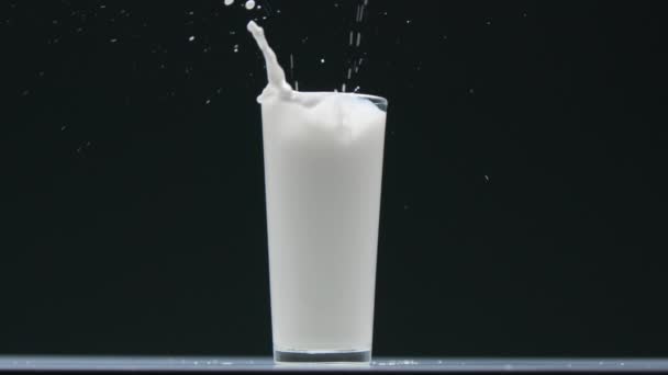 Widok z boku borówka spada do szklanki z mlekiem i zrobić plusk — Wideo stockowe