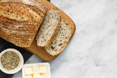 Peçetede ekmek ve tereyağı, üst manzara. Kahvaltıda taze ekmek ve organik tereyağı. Beyaz mermer masa üzerinde kırsal ekşi ekmek.