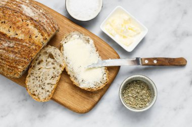 Peçetede ekmek ve tereyağı, üst manzara. Kahvaltıda taze ekmek ve organik tereyağı. Beyaz mermer masa üzerinde kırsal ekşi ekmek.