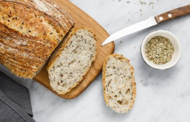 Peçeteye tereyağı sürülmüş taze ev yapımı ekşi ekmek. Kahvaltıda taze ekmek ve organik tereyağı. Beyaz mermer masada zanaatkar ekmeği.