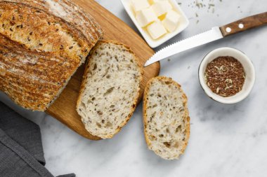 Peçeteye tereyağı sürülmüş taze ev yapımı ekşi ekmek. Kahvaltıda taze ekmek ve organik tereyağı. Beyaz mermer masada zanaatkar ekmeği.