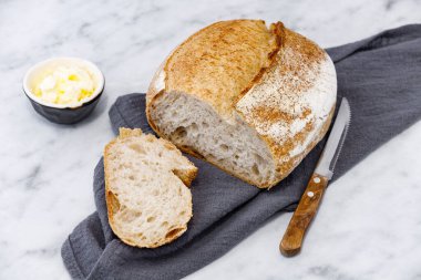 Modern peçetenin üzerinde tereyağlı bir kavanoz ekşi ekmek. Mermer yüzeyde kırsal ekmek.  