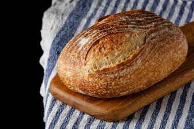 Geleneksel buğday taze kırsal ekmek, tahta kesim tahtası ve havluyla dilimlenmiş. Esnaf ekmeği. Bir somun ekmek.