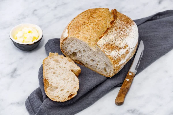 Modern peçetenin üzerinde tereyağlı bir kavanoz ekşi ekmek. Mermer yüzeyde kırsal ekmek.  