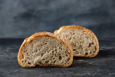 Siyah arka planda dilimlenmiş ekmek, iki yarım buğday ekmeği. Geleneksel buğday taze kırsal ekmek.