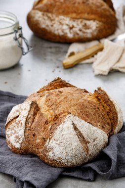Peçeteye keten dökülmüş buğday ekmeği. Ekşi ekmek ve bir kavanoz un.