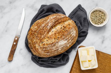 Peçetede ekmek ve tereyağı, üst manzara. Kahvaltı için taze ekmek ve organik tereyağı. Beyaz mermer masa üzerinde kırsal ekşi ekmek.