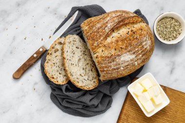 Peçeteye tereyağı sürülmüş taze ev yapımı ekşi ekmek. Kahvaltıda taze ekmek ve organik tereyağı. Beyaz mermer masada zanaatkar ekmeği.