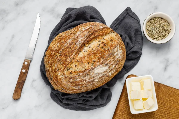 Peçetede ekmek ve tereyağı, üst manzara. Kahvaltı için taze ekmek ve organik tereyağı. Beyaz mermer masa üzerinde kırsal ekşi ekmek.