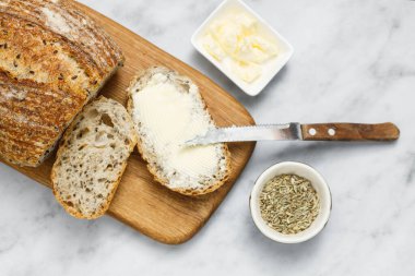 Beyaz mermer masada ekmek ve tereyağı. Kahvaltıda taze ekmek ve organik tereyağı. Rustik ekşi ekmek..