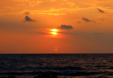 kırmızı güneş ile deniz üzerinde gün batımı çağrıştıran immagine