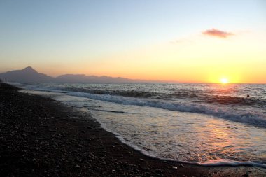 Güneş batarken ön taraftaki denizle birlikte