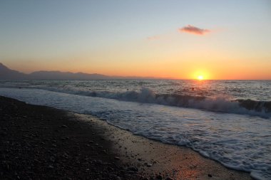 Güneş batarken ön taraftaki denizle birlikte