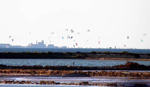 Stagnone Nature Reserve or natural reserve of the \'Saline dello Stagnone\' near Marsala and Trapani, Sicily, Italy, salt flats with sportsmen doing kitesurfing in the background