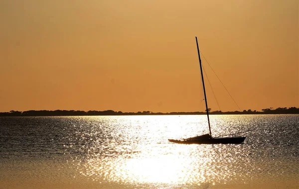 Stagnone Nature Reserve or natural reserve of the \'Saline dello Stagnone\' near Marsala and Trapani, Sicily, Italy, sailboat moored on the sea at sunset and headland on the background