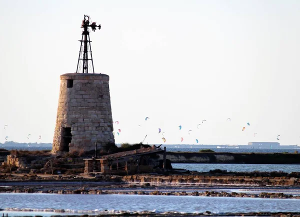 Stagnone Nature Reserve or natural reserve of the \'Saline dello Stagnone\' near Marsala and Trapani, Sicily, Italy, tower in the foreground on the sea with sportsmen doing kitesurfing in the background