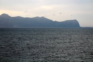 Denizin üzerinde gün batımının anımsatıcı görüntüsü. Arka planda burunların silueti var.