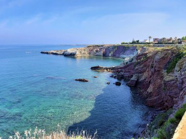 Yazın sarp bir kıyı, deniz ve mavi gökyüzü olan bir deniz hortumunun canlandırıcı görüntüsü.