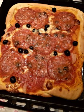 Baharatlı salam, zeytin, domates ve mozzarella ile ev yapımı dikdörtgen pizzanın canlandırıcı görüntüsü