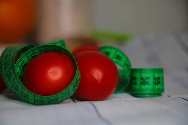 red tomatoes and green tape measure isolated  on the table