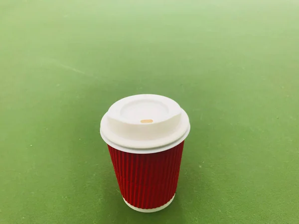 Cangkir kertas merah kopi panas diletakkan di lantai hijau muda — Stok Foto