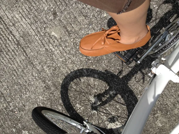 茶色のパンツと革の靴を履いた男が白い自転車に乗っている — ストック写真