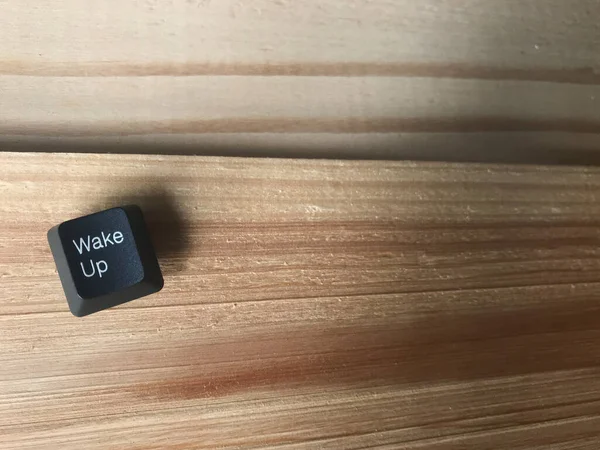 コンピュータのキーボードから黒いボタンをウェイクアップフレームの右側にコピースペースのあるスタジオで天然ゴム板に置きます — ストック写真