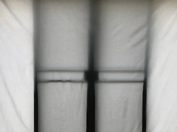 white cotton curtain in front of black sliding door in daylight making mysterious shadow