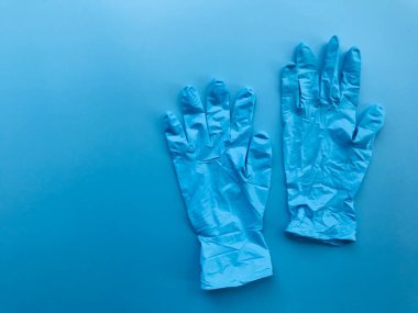 boş mavi arkaplanda bir çift tıbbi eldiven ve çerçevenin sol tarafında kopya alanı var.
