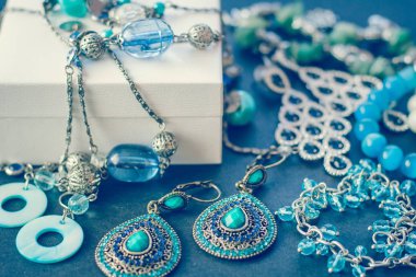 Aksesuar ve süslemeler üzerinde siyah bir arka plan, hediye kutusu, küpe, bilezik, kolye